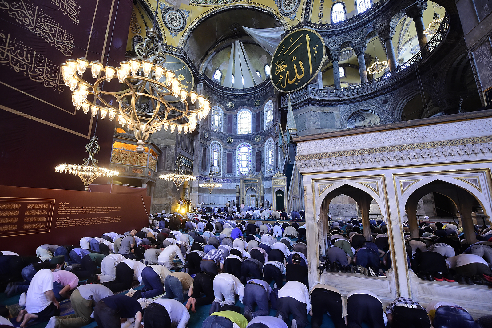 People pray inside the Byzantine-era Hagia Sophia, with sail-like drapes, top, covering mosaics, following the inaugural Friday prayers, in the historic Sultanahmet district of Istanbul, Friday, July 24, 2020. Mosaics depicting Christian figures were covered, in line with Islamic traditions that bar the depiction of figures. Worshipers held the first Muslim prayers in 86 years inside the Istanbul landmark that served as one of Christendom's most significant cathedrals, a mosque and a museum before its conversion back into a Muslim place of worship. (AP Photo/Yasin Akgul)